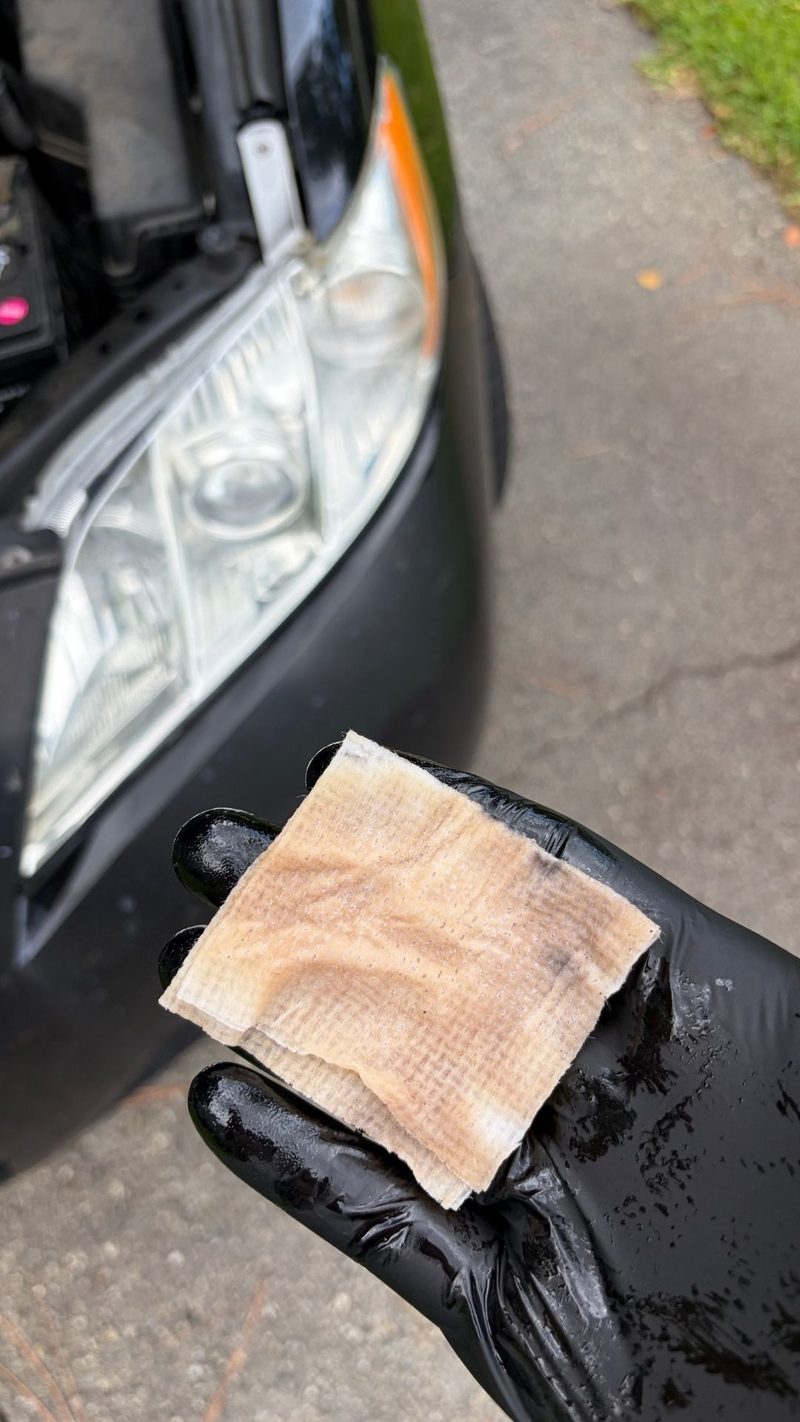 Applicator pad covered in oxidation sanded off a headlight lens